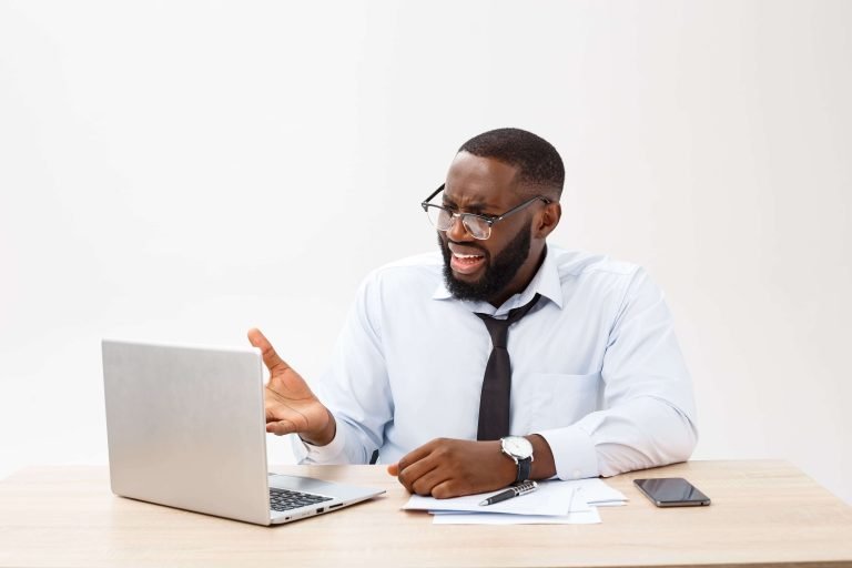 Een zakenman aan een bureau met een laptop, die fouten tegenkomt tijdens het maken van een website.